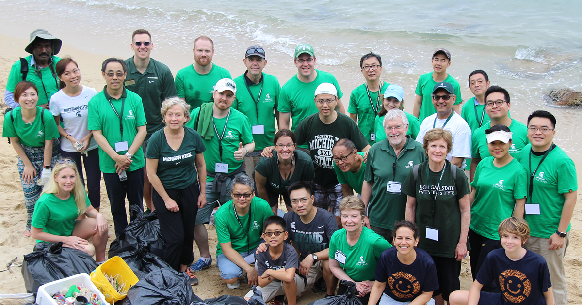 Global alumni and friends cleaning a local beachfront during an international alumni reunion in Hong Kong